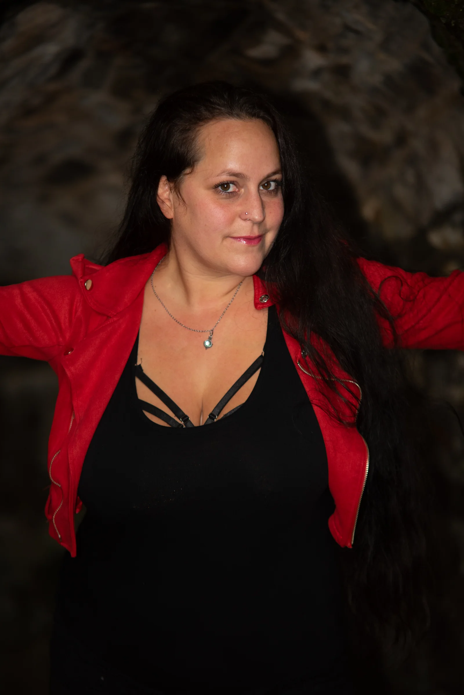 Lostplace-Portrait einer Frau in roter Jacke vor dunklem Mauerwerk an der Burg Windeck