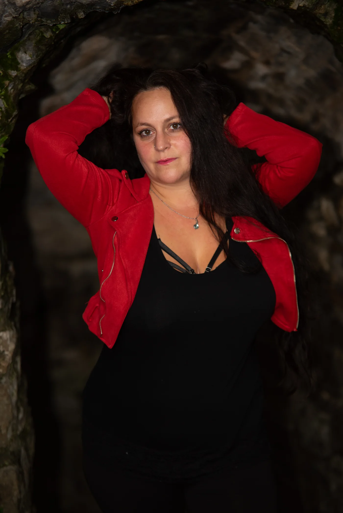 Frau in roter Jacke posiert unter einem Steinbogen an der Burg Windeck