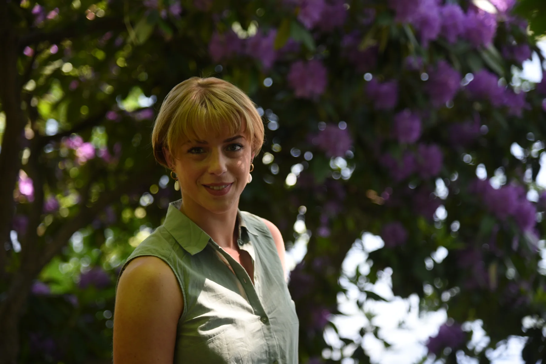 Natürliches Outdoor-Portrait einer Frau vor violetten Blüten